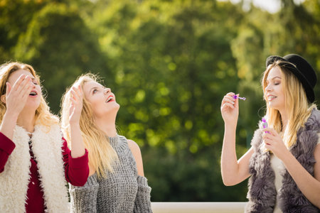 Vacations joy, friendship concept. Women friends having fun blowing soap bubbles outdoor.の写真素材