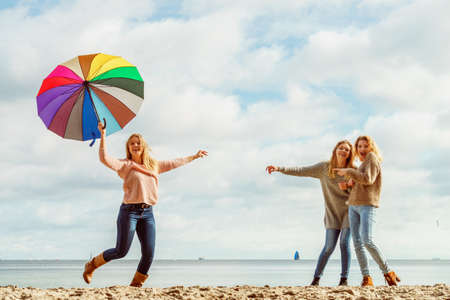 Three women full of joy having great time together. One woman holding colorful umbrella.の写真素材