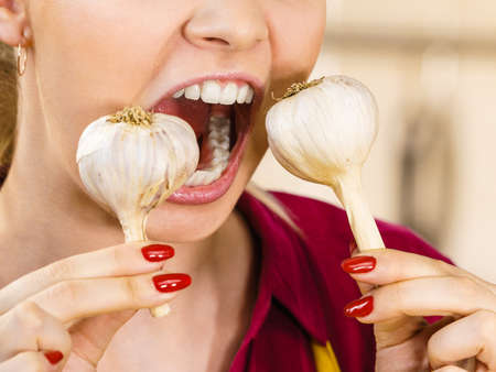 Crazy young woman having fun eating garlic vegetable. Healthy food, fighting disease concept.の写真素材