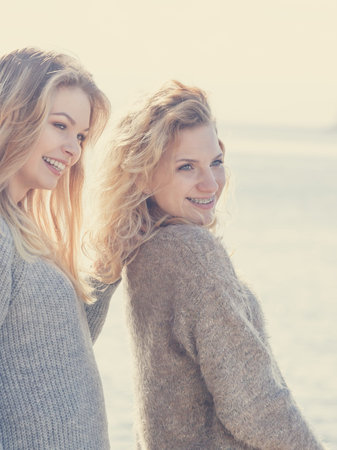 Two fashionable women wearing stylish outfits during warm autumnal weather spending their free time...