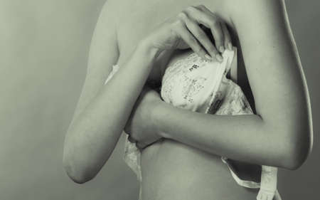Bosom concept. Slim attractive naked woman dressing up or putting on her lacy bra, black aad white photoの写真素材