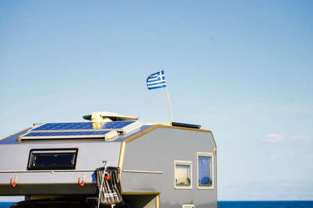 Camping truck on beach with Greek national flag on roof. Traveling, adventure concept.の写真素材