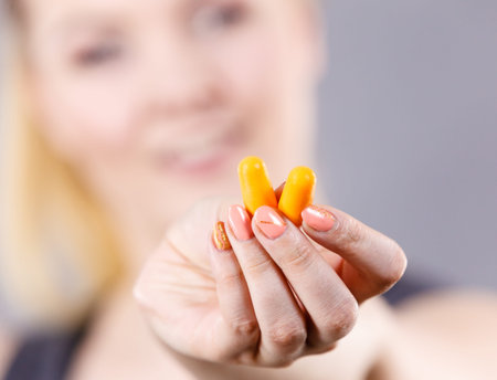 Woman holding protective ear plugs. Getting rid on noise in loud place, hearing protection concept.