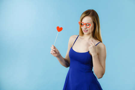Woman holding carnival accessoies on stick having fun. Studio shot on blue background.の写真素材