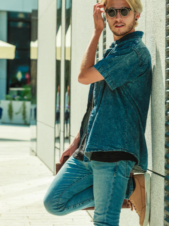 Men fashion, urban style clothing concept. Hipster guy walking through city wearing jeans outfit and...
