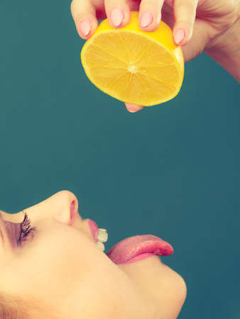 Healthy diet, refreshing food full of vitamins. Woman with open mouth holding sour citrus fruit lemon sticking tongue out.の写真素材
