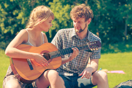 Adventure, tourism, enjoying summer time together - young couple tourists having fun playing guitar in campingの写真素材