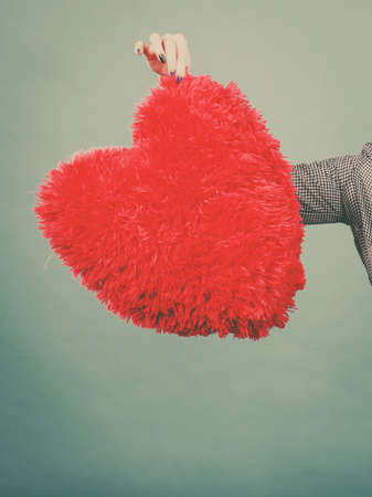 Love, romance, valentines day gift idea concept. Woman holding big red fluffy pillow in heart shapeの写真素材
