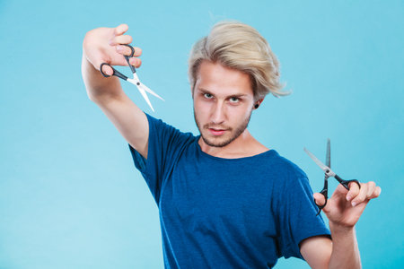 Haircut coiffure haircare concept. Passionate male hairdresser holding scissors showing work tools...