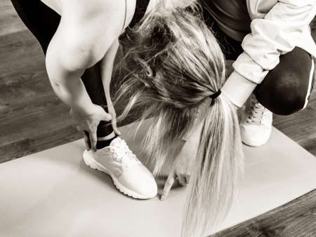 Young blonde woman in sportswear stretching body, working out with her trainer. Training at home, being fit and healthy.の写真素材