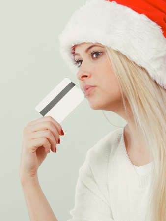 Buying Christmas gifts concept. Woman in Santa hat holding credit card about to buy presents.の写真素材