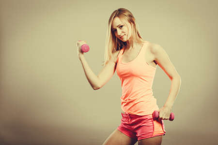 Bodybuilding. Strong fit woman exercising with dumbbells. Muscular blonde girl lifting weights studio shotの写真素材