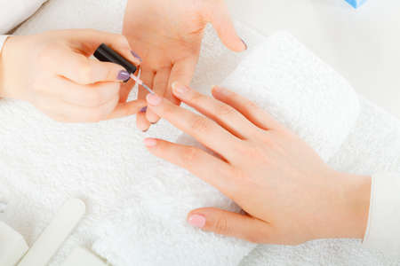 Closeup of beautician painting nails of female client. Woman in beauty spa salon doing manicureの写真素材