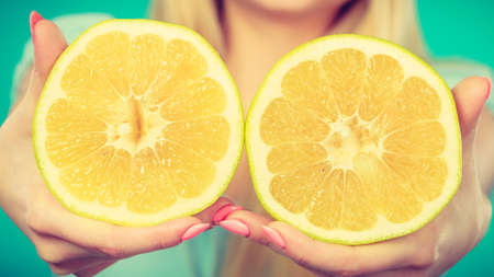Halfs of yellow grapefruit citrus fruit in female hands closeup. Woman dietician recommend healthy diet nutrition.の写真素材