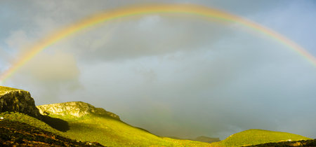 Beautiful rainbow on dark sky with clouds after rain. Weather forecasting, beauty in nature concept.