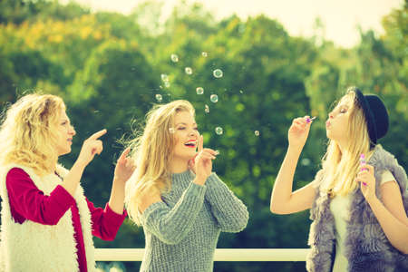 Vacations joy, friendship concept. Women friends having fun blowing soap bubbles outdoor.の写真素材