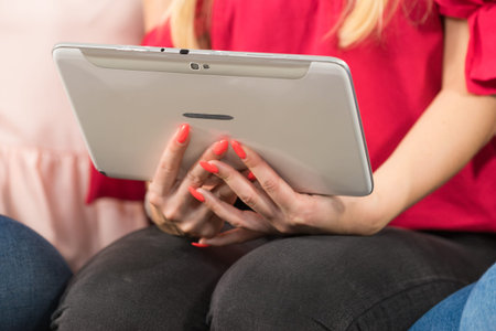 Women sitting on sofa surfing on the internet using smart digital pc tablet