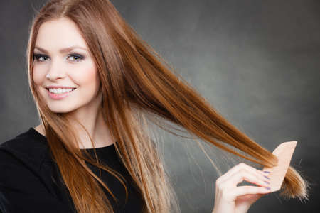 Preparation to evening party. Gorgeous attractive woman combing her long straight smoothy healthy hair before go out. Party and celebration concept.の写真素材
