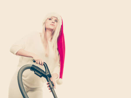 Woman vacuuming the house. Teen girl in santa helper hat with vacuum cleaner. Christmas time and housework concept.の写真素材