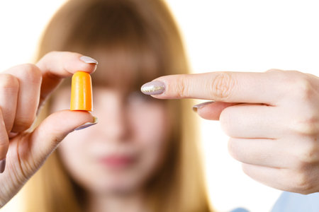 Woman holding protective ear plugs. Getting rid on noise in loud place, hearing protection concept.