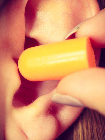 Woman putting ear plugs into her ears getting rid on noise in loud place.の写真素材