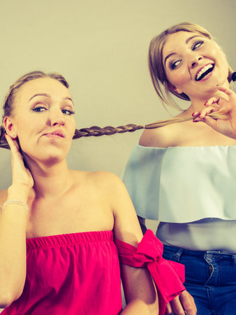 Two young pretty women being mad at each other having argue fight pulling hair. Friendship rivaly...