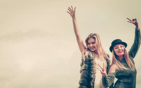 Two fashionable women wearing stylish outfits during warm autumnal weather spending their free time outdoorの写真素材