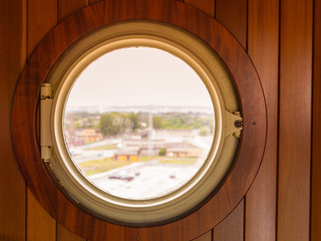 Ship bull's eye, porthole window in wooden wall looking out at port