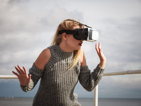 Young woman testing VR glasses outside. Female wearing virtual reality headset during spring...