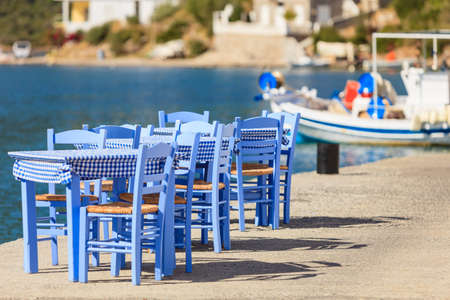 Seaside blue table and chairs open cafe outdoor restaurant in Greece on sea shore. Summer vacation on resort.の写真素材