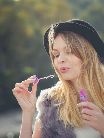 Funny young fashionable hipster teenage woman blowing soap bubbles outdoor having fun.の写真素材