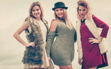 Three fashionable women having presenting pretty stylish outfits. Style, fashion, friendship concept.の写真素材