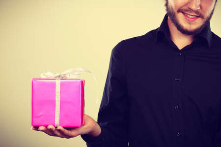 People celebrating xmas, love and happiness concept - cool young man holding present pink gift box in handの写真素材
