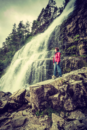Tourist woman at Svandalsfossen in Norway, powerful waterfall in norwegian mountains. National tourist Ryfylke route.の写真素材