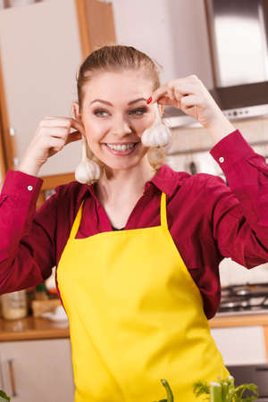 Woman holding healthy herb, two fresh natural garlic pretending it's earrings. Healthy eating and dieting concept.の写真素材