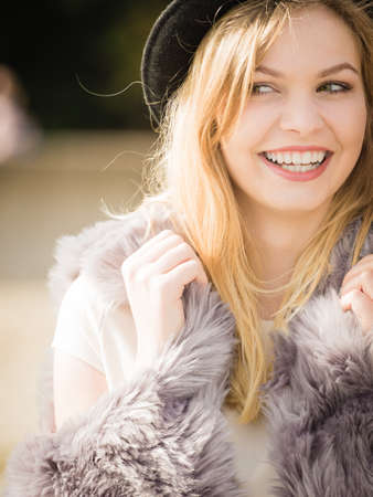 Beautiful young blonde woman wearing fedora hat, long warm fur sweater jumper outdoorの写真素材