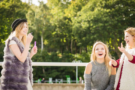 Vacations joy, friendship concept. Women friends having fun blowing soap bubbles outdoor.の写真素材