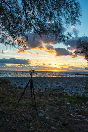 Professional camera taking picture film video of sunrise over sea surface, Greece.