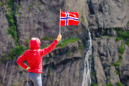 Tourist woman with norwegian flag in rocky stone mountains.の写真素材