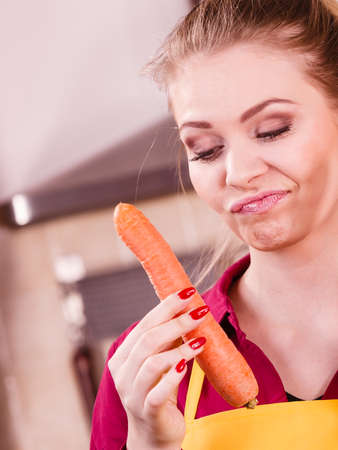 Woman does not like vegetable. Female holding to carrots having grimacing face expression.の写真素材