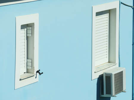 Architectural details outside house. White windows shutters on blue wall of home and air conditioner box.の写真素材