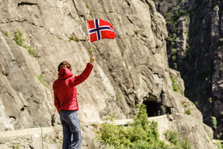 Tourist woman with norwegian flag in rocky stone mountains.の写真素材