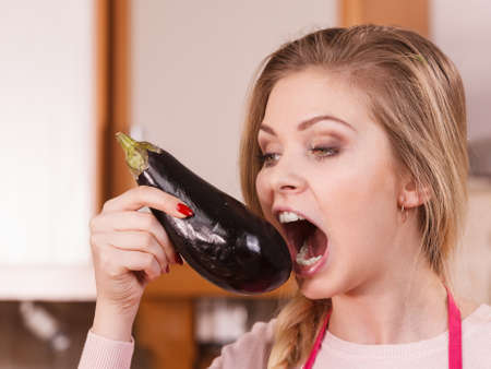 Vegetable having good impact on teeth. Young woman eating biting delicious eggplant.の写真素材