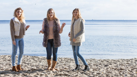 Three fashionable women sisters friends wearing sweaters during warm autumnal weather spending their...