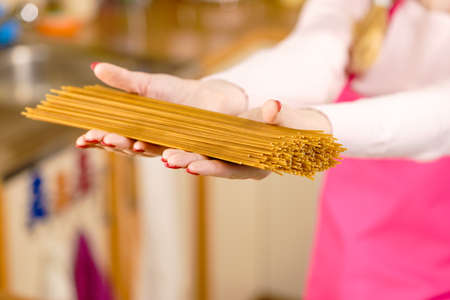Woman holding long pasta macaroni ready to cook spaghetti. Healthy food concept.の写真素材