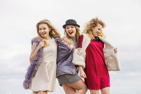 Three fashionable women having presenting pretty stylish outfits. Style, fashion, friendship concept.の写真素材