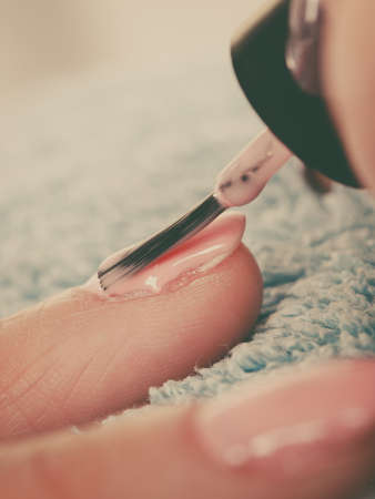 Closeup of beautician painting nails of female client. Woman in beauty spa salon doing manicureの写真素材