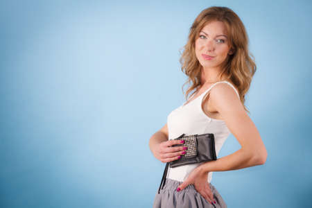 Happy young elegant woman holding purse wallet ready for shopping or partyの写真素材