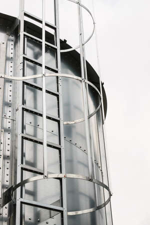 Industrial metal ladder with round protection, railing. Safety rules, agricultural industry objects details.の写真素材