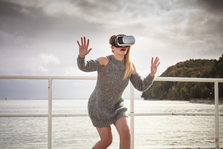 Young woman testing VR glasses outside. Female wearing virtual reality headset during spring...